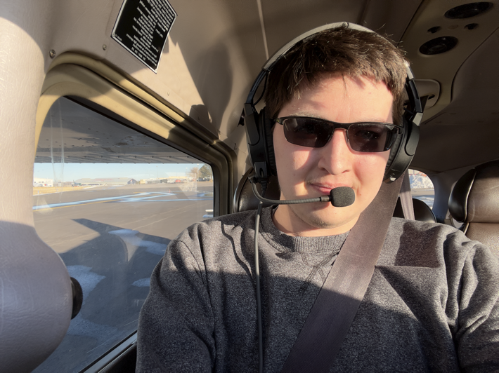 My profile picture. Selfie taken before takeoff on my first solo flight as a student pilot at Centennial Airport (KAPA) in Colorado with my sunglasses and aviation headset on.